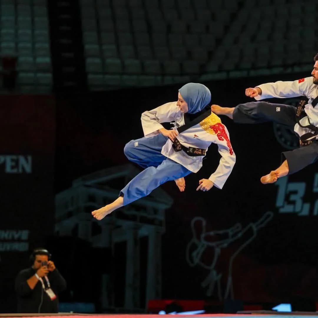 Müsabaka alanında havada tekme atan taekwondo sporcusu